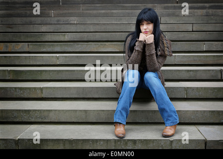 sad woman sitting on steps outside Stock Photo