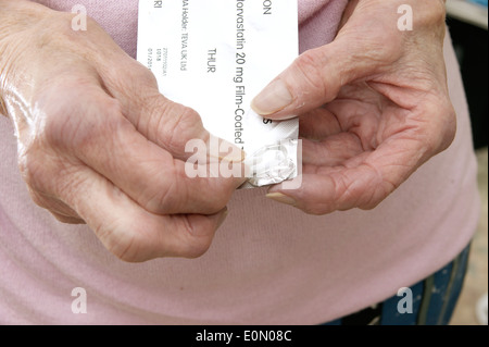 Elderly woman taking Atorvastatin tablets (statins) Stock Photo