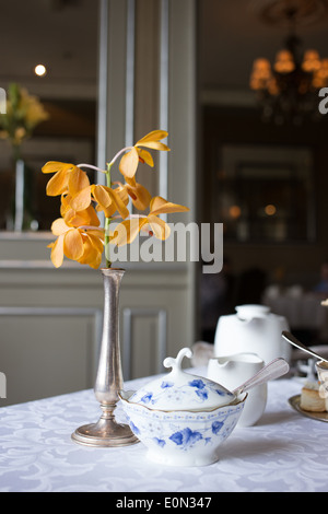 Bowl of sugar next to elegant vase of flowers in formal dining room. Stock Photo