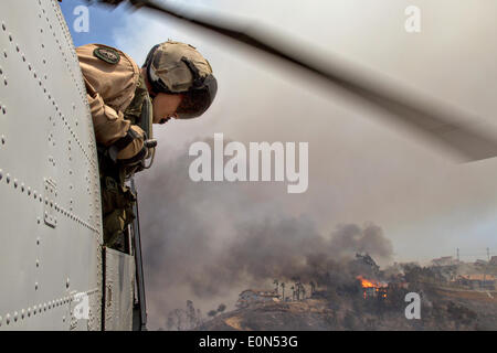 A US Marine looks out from a CH-46 Sea Knight helicopter assisting in fighting the Cocos wildfire as it burns the foothills destroying home May 15, 2014 around San Marcos, California.  Evacuations forced more than 13,000 people from their homes as the fire burned across San Diego County. Stock Photo