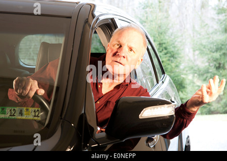 Driver leaning out window of SUV with a confused look on his face Stock Photo