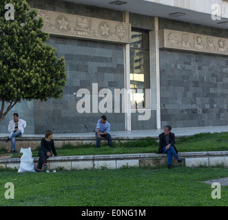 Albanians looking in different directions sitting outside building, Tirana, Albania Stock Photo