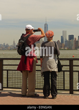 American tourists photographing the Manhattan skyline from Liberty Island Stock Photo