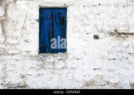 Old blue shutter in a peeling brick wall Stock Photo