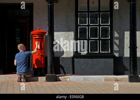 Man painting a pillar box red, Kirkland, Kendal, Cumbria, England UK Stock Photo