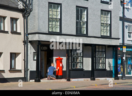 Man painting a pillar box red, Kirkland, Kendal, Cumbria, England UK Stock Photo