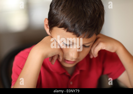 Young boy studying for his homework with his head in his hands - with very shallow depth of field Stock Photo