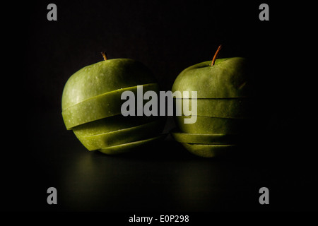 Still life two apples sliced up against dark background Stock Photo
