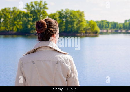 A woman with a chignon looking at the river during a nice sunny spring morning Stock Photo