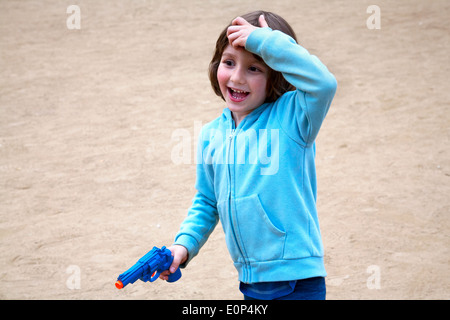 Five year old boy smiling and playing with plastic gun, Barcelona, Spain. Stock Photo