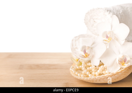 Spa still life of white orchid flower, towel and shell with beads on wood background, isolated Stock Photo