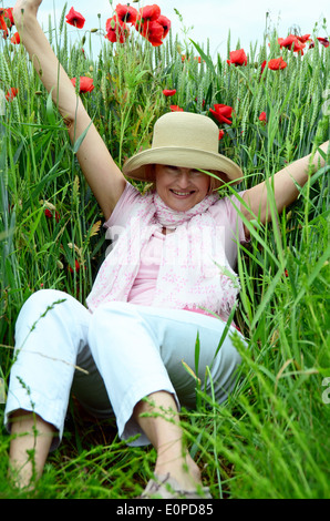 Woman with hat sitting on meadow Stock Photo