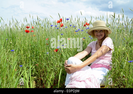 Woman with hat sitting on meadow Stock Photo