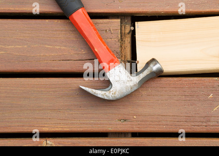 Horizontal photo of old hammer next to aged wood and exposed rusty nails with new cedar board being installed Stock Photo