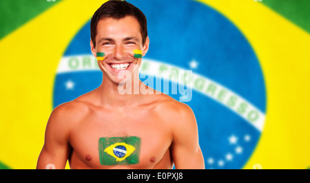 Happy brazilian fan standing over brazil flag background Stock Photo