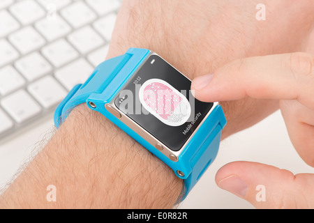 Man is scanning fingerprint for mobile security with blue smart watch. Stock Photo