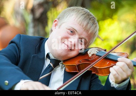 Portrait of young handicapped violinist practicing outdoors. Stock Photo