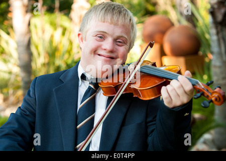 Close up portrait of friendly handicapped boy playing violin outdoors. Stock Photo