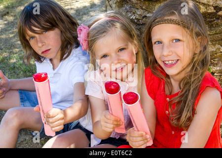 Portrait of youngsters enjoying ice pops outdoors. Stock Photo