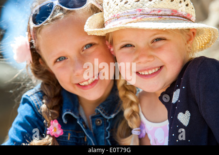 Close up face shot of two young girlfriends smiling with heads together outdoors. Stock Photo