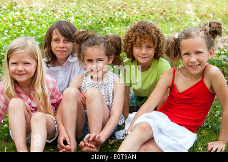 Children sitting together in flower field Stock Photo