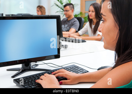 Young female student typing on computer keyboard in classroom. Stock Photo