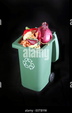 Recycling rubbish or garbage bin with vegetable scraps inside to turn to compost on a black background. Stock Photo