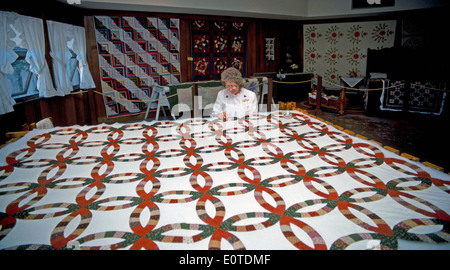 A woman works on a large quilt to demonstrate an early American handicraft at the Ozark Folk Center, a living history state park in Arkansas, USA. Stock Photo