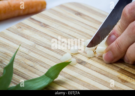 closeup of fingers slicing with a small knife fresh clean leeks Stock Photo