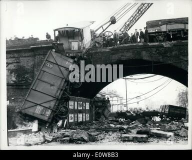 Jan. 01, 1962 - Crash hits rush hour: Two goods trains crashed last night on a junction above Kentish Town Road in London. A number of wagons fell down into the street. Fourteen persons were slightly injured. This morning thousands of Londoners were delayed during the rush hour as buses and many trains had to be diverted. Photo shows Rubble blocks the road under the railway bridge this morning. A guard's van dangles from parapet. Below one of the wagons that crashed. Stock Photo