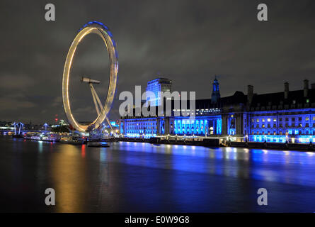 The London Eye on the River Thames and the illuminated London Aquarium, formerly County Hall, at night, Southbank, London Stock Photo