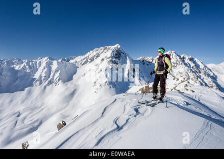 Ski tourer standing on the summit of Seespitz mountain, Deutschnonsberg, Ilmenspitze mountain at the back, Proveis, Ulten Valley Stock Photo