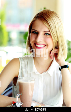 Young smiling woman sitting in cafe Stock Photo