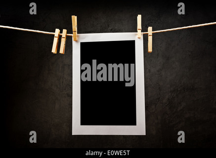 Photography paper attached to rope with clothes pins with copy space for your image over grunge texture. Stock Photo