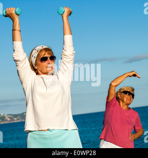 Senior ladies doing fitness exercises on beach. Stock Photo