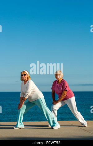 Senior women doing stretching exercises at seafront. Stock Photo