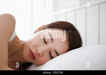 a woman sleeping in bed with white sheets Stock Photo