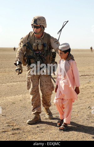 A US Marine with Weapons Company, 1st Battalion, 7th Marine Regiment walks with an Afghan child during a counter insurgency mission April 28, 2014 in Helmand province, Afghanistan. Stock Photo