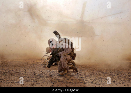 US Marines with Weapons Company, 1st Battalion, 7th Marine Regiment take cover from the dust kicked up by a CH-53E Super Sea Stallion helicopter during a counter insurgency mission April 28, 2014 in Helmand province, Afghanistan. Stock Photo