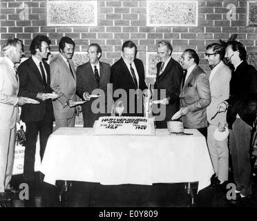 Actor John Wayne cuts his cake surrounded by friends Stock Photo