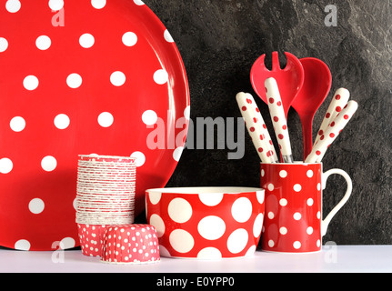 Modern Red and White Polka Dot Kitchen with large platter plate, cupcake pans, bowl, coffee mug, cutlery and serving spoons Stock Photo