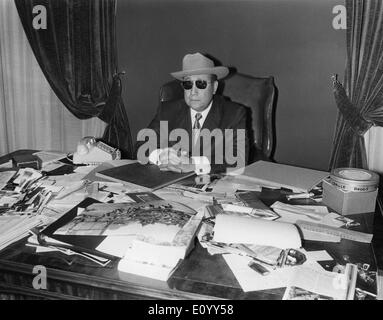 Nov. 3, 1971 - JEAN-PIERRE MELVILLE wearing a cowboy hat and sunglasses sitting at his desk. Stock Photo