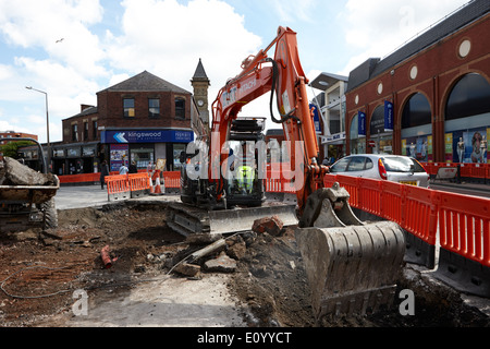 man operating hitachi excavator digging up city streets Preston Lancashire UK Stock Photo