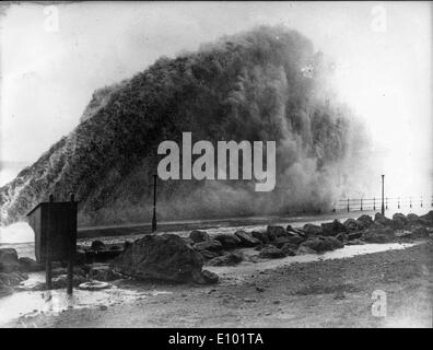 Bad Weather - Giant ocean wave crashes over a coastal boardwalk promenade during a heavy storm Stock Photo