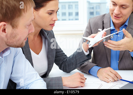 Three engineers discussing a small model of a plane held by female Stock Photo