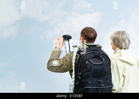 Backs of senior hikers with binoculars on trip Stock Photo