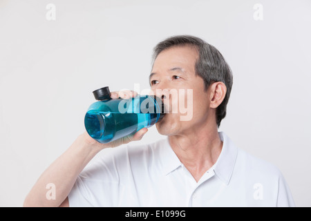 an old man drinking water from a bottle Stock Photo