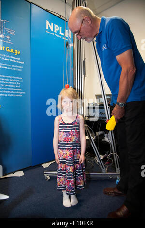 Visitor, a girl aged 4 years (model released), photographed whilst her height is being measured very accurately by a member of the NPL staff (NOT model released) using a Laser Height Gauge (which uses a He-Ne Stabilised Laser) during an Open Day (which happens around every two years) school trip / visit at the National Physical Laboratory (NPL), Teddington. London. UK. Stock Photo