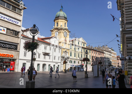 City center pedestrian zone in Rijeka, Croatia, with 19th century Baroque clock tower and people walking up and down the street Stock Photo