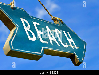 Low angle view of rustic weathered 'Beach' sign against blue sky summer holiday vacation concept Stock Photo